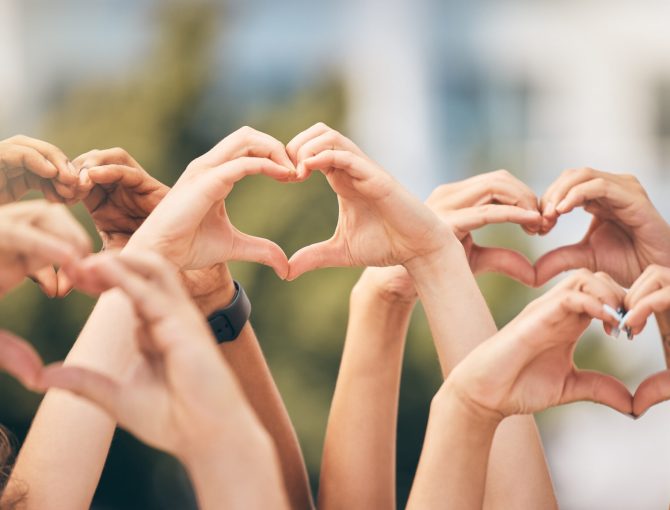 Hand, heart and love with a group of people making a sign with their hands outdoor together in the day. Crowd, freedom and community with man and woman friends doing a gesture to promote health.